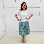 Green print, midi length, A line skirt, with stretch waistband. Worn with relaxed fit, loose line, scoop neckline, short sleeve, white bamboo top.