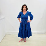 Sapphire background with a deep teal and black very discreet and discerning animal print. V-neck. Gathered sleeve at the shoulder. Roomy Sleeves that can be worn at long sleeves or three quarters. Cuffed at the wrist with discreet elastic threaded through. 7/8s in length. Two tier skirt. Lower tier with a subtle ruffle. Fitted at the waist with elastic threaded through the back discreetly for comfort and ease of getting on. Sash worn on waist. Centre back zipper.