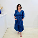 Sapphire background with a deep teal and black very discreet and discerning animal print. V-neck. Gathered sleeve at the shoulder. Roomy Sleeves that can be worn at long sleeves or three quarters. Cuffed at the wrist with discreet elastic threaded through. 7/8s in length. Two tier skirt. Lower tier with a subtle ruffle. Fitted at the waist with elastic threaded through the back discreetly for comfort and ease of getting on. Sash worn on waist. Centre back zipper.