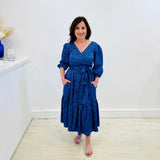 Sapphire background with a deep teal and black very discreet and discerning animal print. V-neck. Gathered sleeve at the shoulder. Roomy Sleeves that can be worn at long sleeves or three quarters. Cuffed at the wrist with discreet elastic threaded through. 7/8s in length. Two tier skirt. Lower tier with a subtle ruffle. Fitted at the waist with elastic threaded through the back discreetly for comfort and ease of getting on. Sash worn on waist. Centre back zipper.