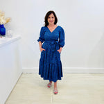 Sapphire background with a deep teal and black very discreet and discerning animal print. V-neck. Gathered sleeve at the shoulder. Roomy Sleeves that can be worn at long sleeves or three quarters. Cuffed at the wrist with discreet elastic threaded through. 7/8s in length. Two tier skirt. Lower tier with a subtle ruffle. Fitted at the waist with elastic threaded through the back discreetly for comfort and ease of getting on. Sash worn on waist. Centre back zipper.