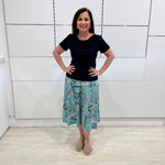 Green print, midi length, A line skirt, with stretch waistband. Worn with short sleeve, cowl neckline , black bamboo top.