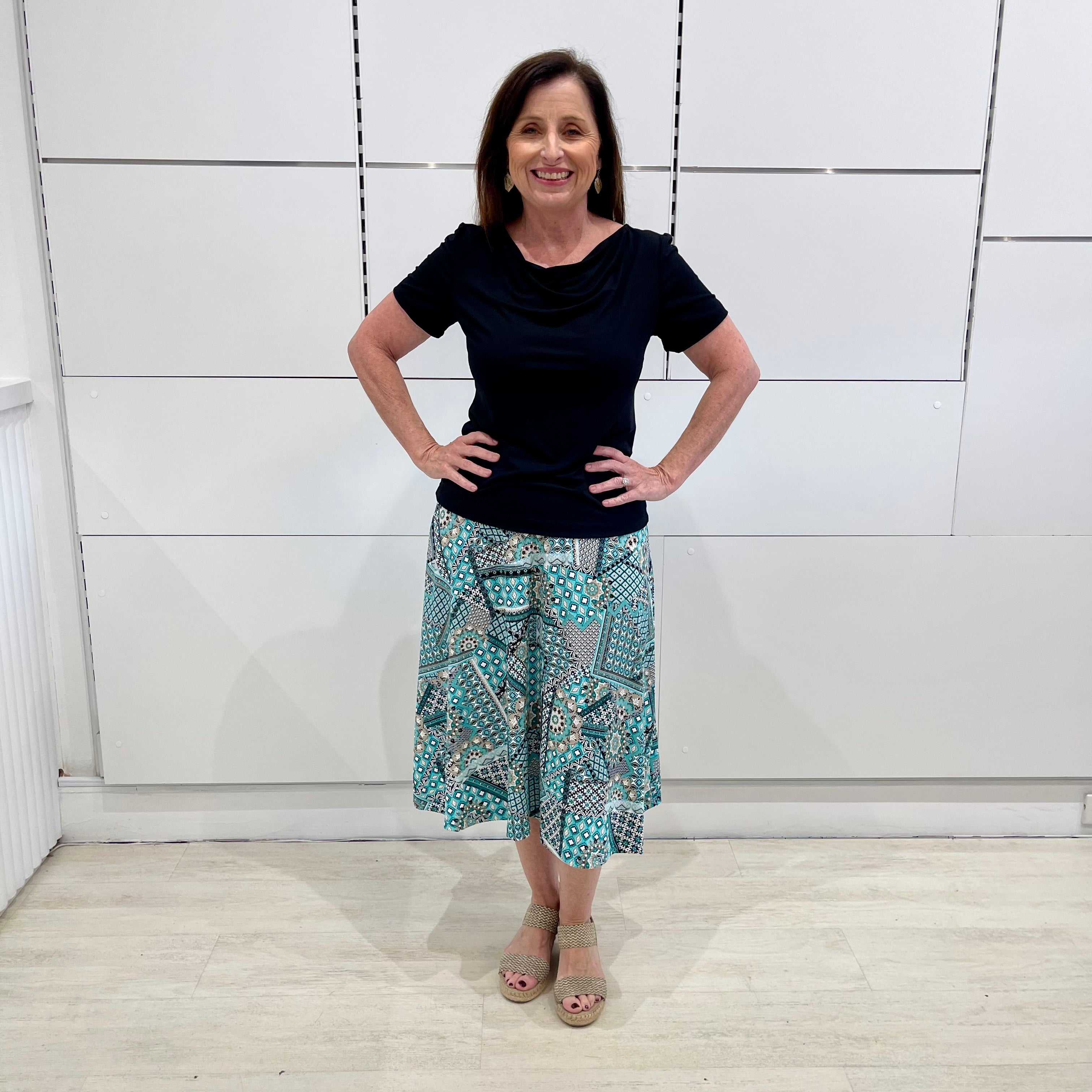 Green print, midi length, A line skirt, with stretch waistband. Worn with short sleeve, cowl neckline , black bamboo top.