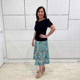 Green print, midi length, A line skirt, with stretch waistband. Worn with short sleeve, cowl neckline , black bamboo top.
