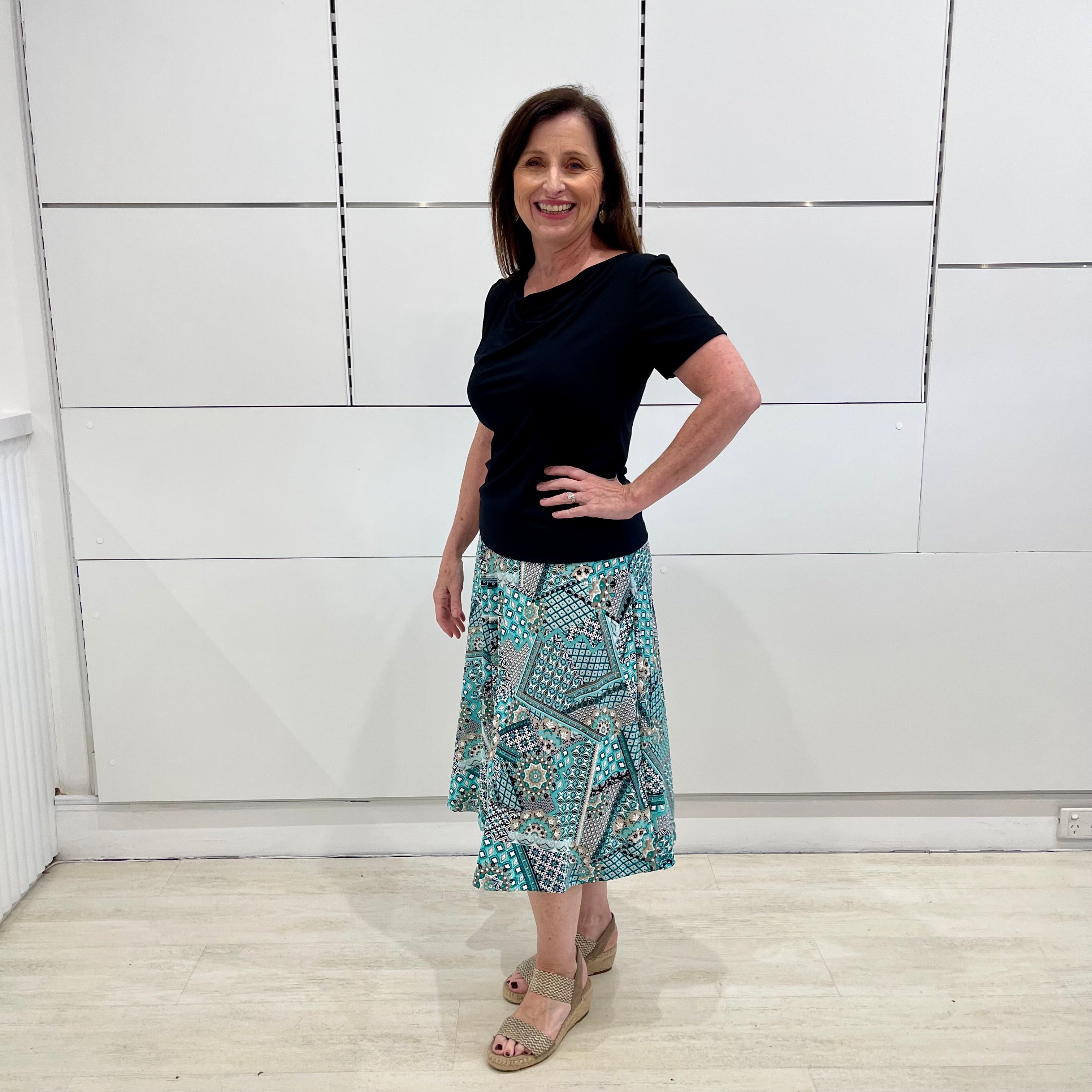 Green print, midi length, A line skirt, with stretch waistband. Worn with short sleeve, cowl neckline , black bamboo top.