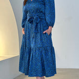 Sapphire background with a deep teal and black very discreet and discerning animal print. V-neck. Gathered sleeve at the shoulder. Roomy Sleeves that can be worn at long sleeves or three quarters. Cuffed at the wrist with discreet elastic threaded through. 7/8s in length. Two tier skirt. Lower tier with a subtle ruffle. Fitted at the waist with elastic threaded through the back discreetly for comfort and ease of getting on. Sash worn on waist. Centre back zipper.