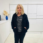 Black fluffy, faux fur, teddy bear jacket with pockets. Worn with black tailored fitted pants and a black and silver sparkly cowl neckline top.