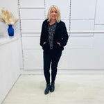 Black fluffy, faux fur, teddy bear jacket with pockets. Worn with black tailored fitted pants and a black and silver sparkly cowl neckline top.