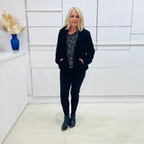 Black fluffy, faux fur, teddy bear jacket with pockets. Worn with black tailored fitted pants and a black and silver sparkly cowl neckline top.