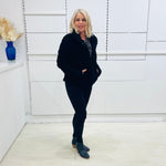 Black fluffy, faux fur, teddy bear jacket with pockets. Worn with black tailored fitted pants and a black and silver sparkly cowl neckline top.