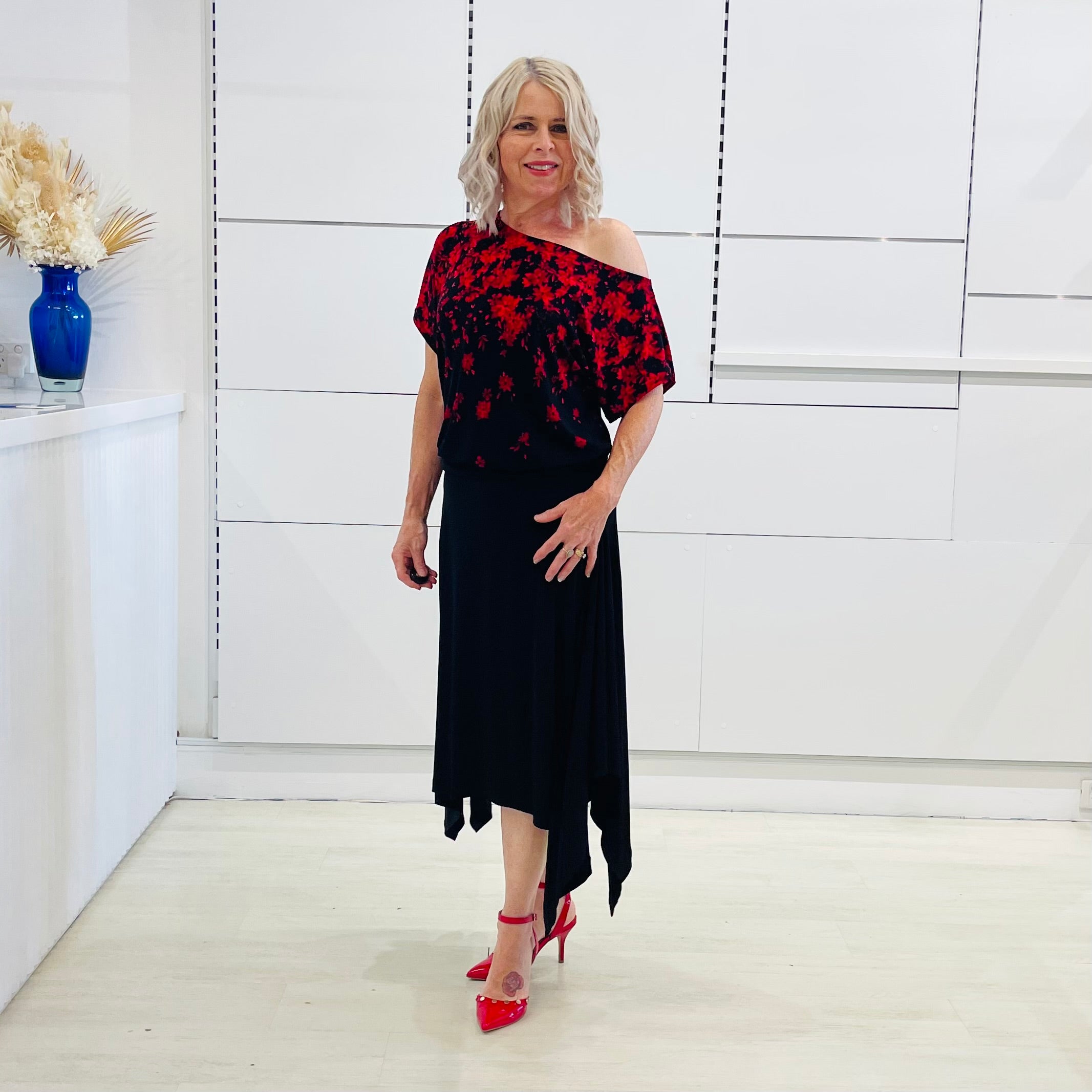 Black & red floral print, off the shoulder, asymmetrical neckline, relaxed fit top, worn with black, handkerchief hemline skirt with elastic waistband.