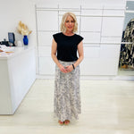 Woman in black top and patterned skirt standing in a modern office setting