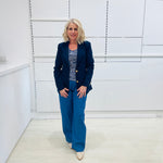 Single breasted, navy blazer for women, with gold buttons. Worn with blue top and blue linen pants.