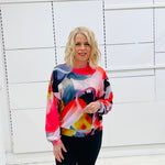 Woman wearing a colorful sweater in front of a white wall