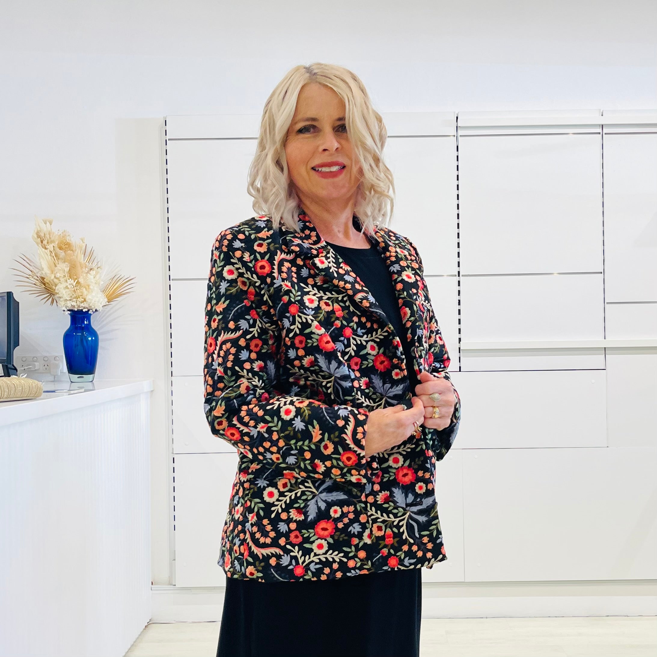 Black silk, with floral embroidery, collar, lapels, 3 button front closure, with pockets jacket. Worn with dressy straight black dress with side seam splits.