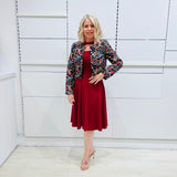 Woman wearing the Penelope dress n rich ruby red, featuring a fit-and-flare, knee length, slihouette, full length sleeves, and a cut out neckline. With embroidered silk bolero Selena Jacket.