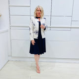 Penelope dress in deep navy blue, worn by model- elegant long sleeve design, knee length, with modern neckline, worn with Navy blue & white embroidered silk jacket, designed and Made in Australia.