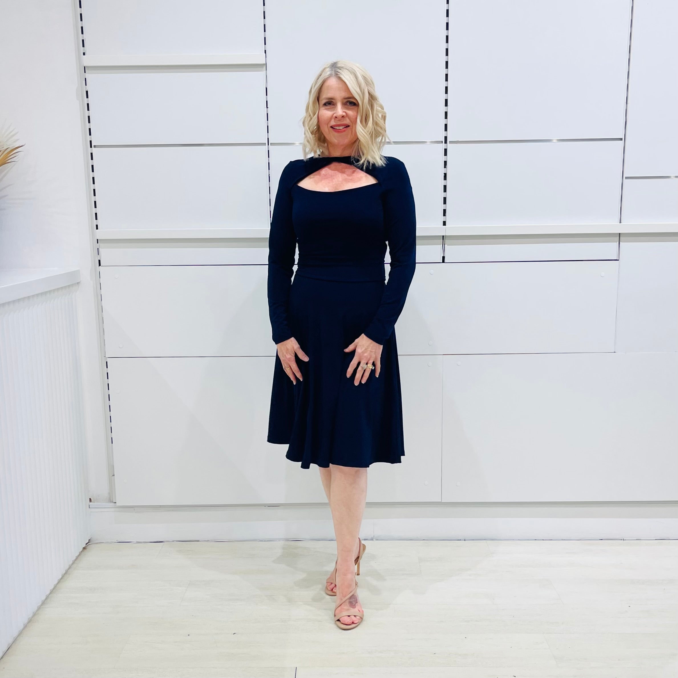 Penelope dress in deep navy blue, worn by model- elegant long sleeve design, knee length, with modern neckline.