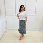 Green,black and white print, stretch, slight a-line skirt, with small ruffle on hemline. Worn with white bamboo, short sleeve, relaxed fit  top.