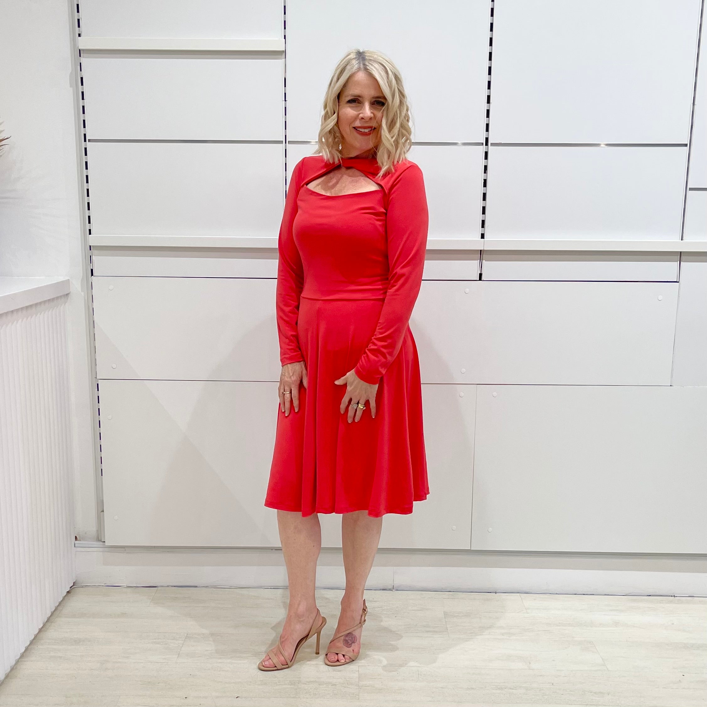 Bright watermelon pink Penelope dress on model- vibrant colour, stretch dress, with feminine silhouette, long sleeve, a-line skirt and keyhole neckline.