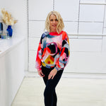 Woman wearing a colorful sweater in a minimalistic room.