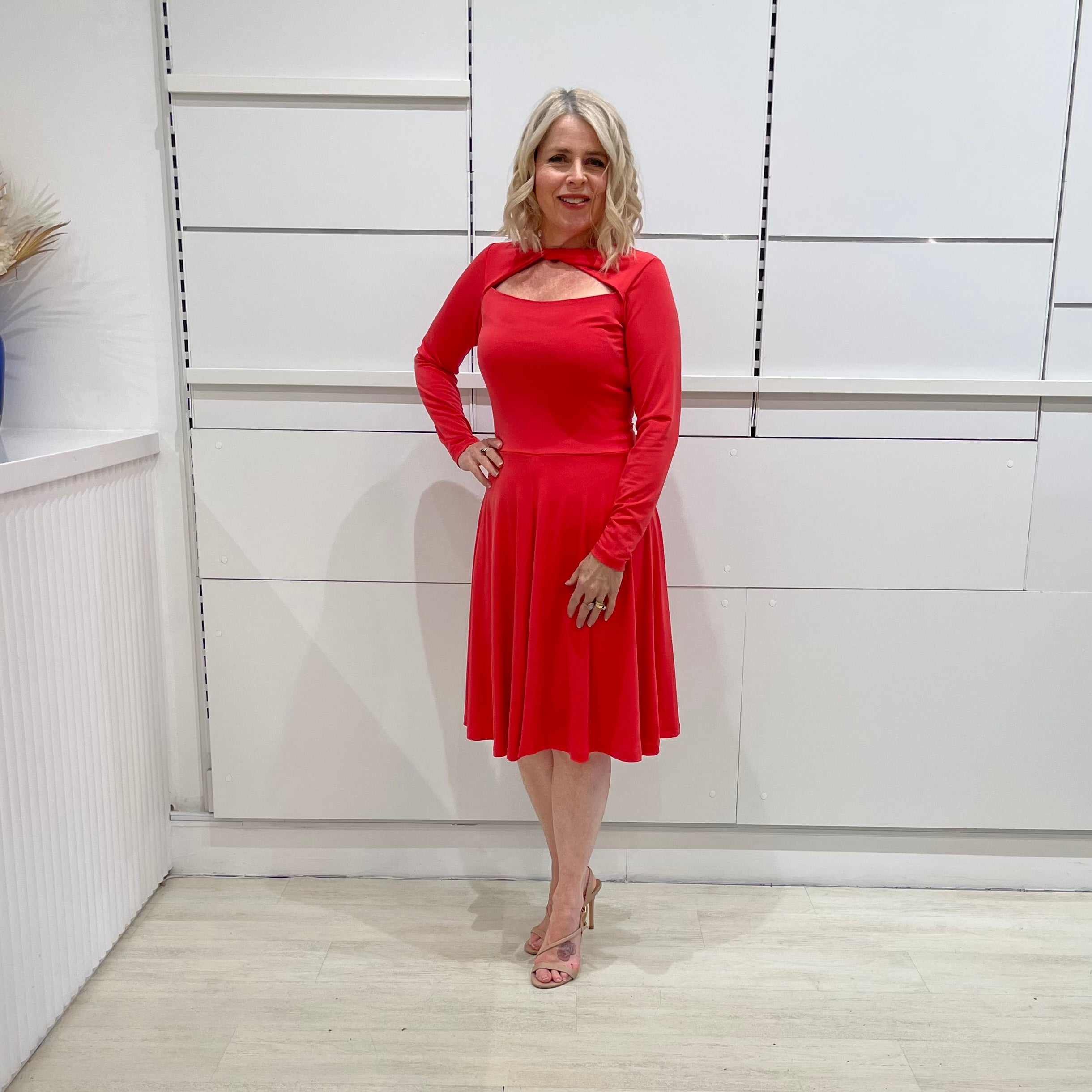 Bright watermelon pink Penelope dress on model- vibrant colour, stretch dress, with feminine silhouette, long sleeve, a-line skirt and keyhole neckline.