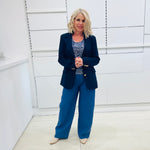 Single breasted, navy blazer for women, with gold buttons. Worn with blue top and blue linen pants.