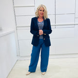 Single breasted, navy blazer for women, with gold buttons. Worn with blue top and blue linen pants.