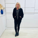 Black fluffy, faux fur, teddy bear jacket with pockets. Worn with black tailored fitted pants and a black and silver sparkly cowl neckline top.