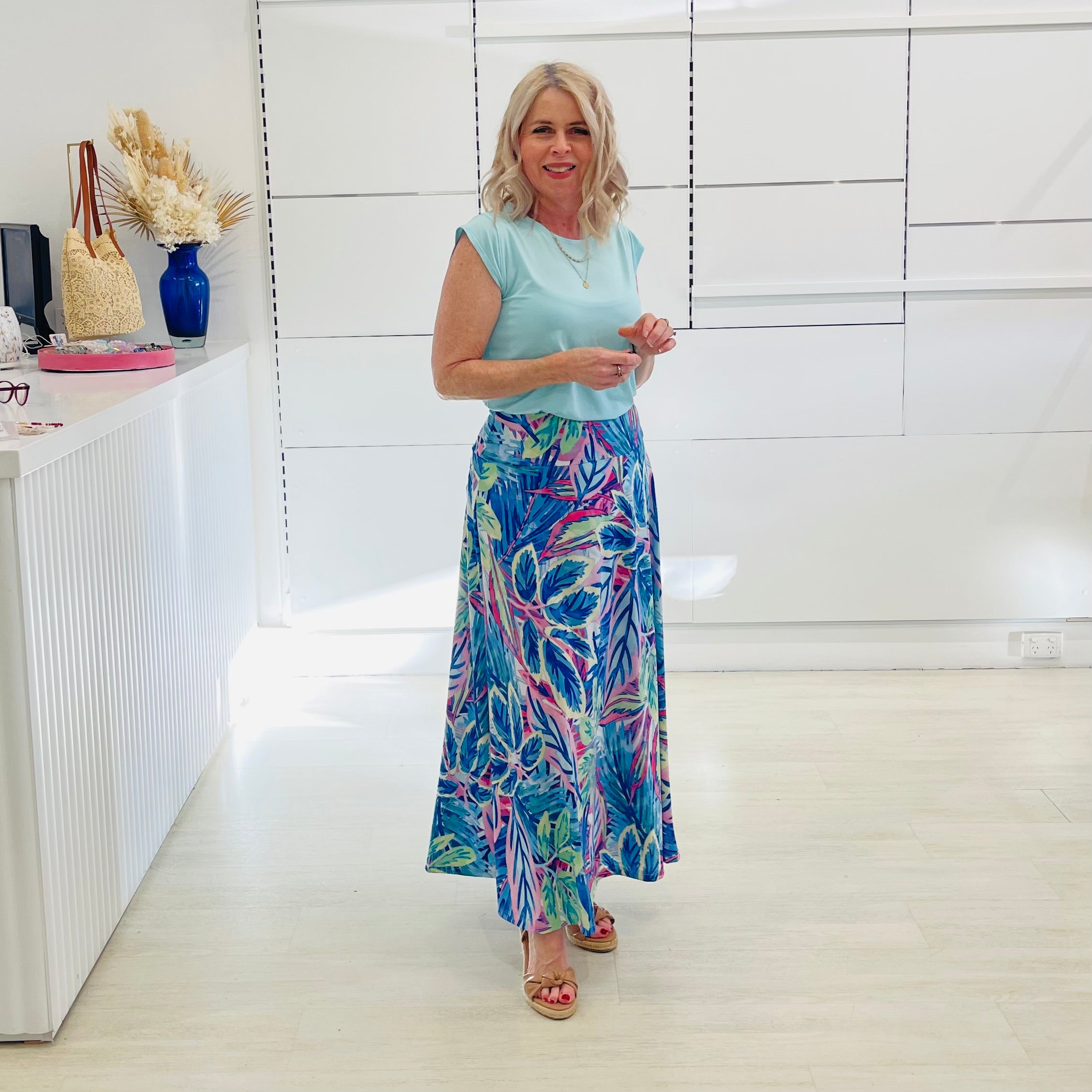 Woman wearing mint green short sleeve t-shirt with long blue floral maxi skirt. 