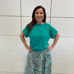 Emerald green bamboo, relaxed fit, scoop neckline , short sleeve, summer top, with band on hem for shape. Worn with long green patterned long, maxi skirt.