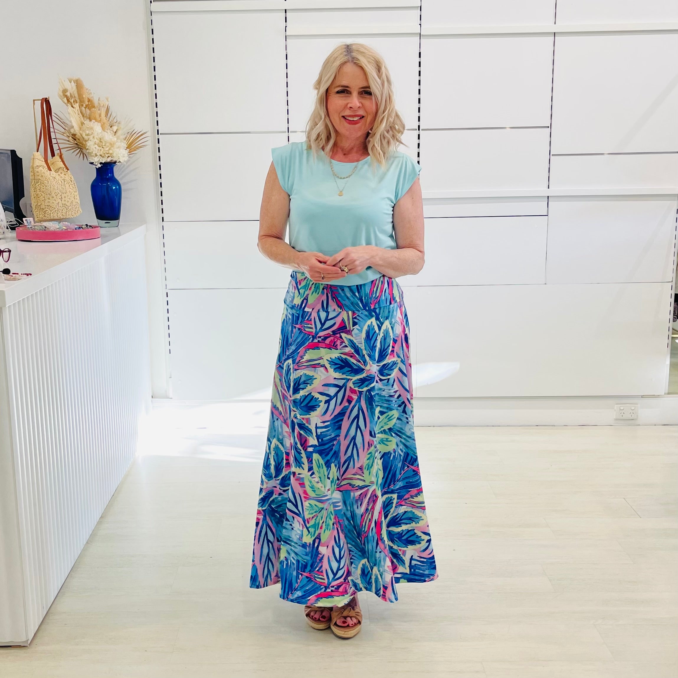 Woman wearing mint green short sleeve t-shirt with maxi long blue floral skirt. 