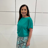 Emerald green bamboo, relaxed fit, scoop neckline , short sleeve, summer top, with band on hem for shape. Worn with long green patterned long, maxi skirt.