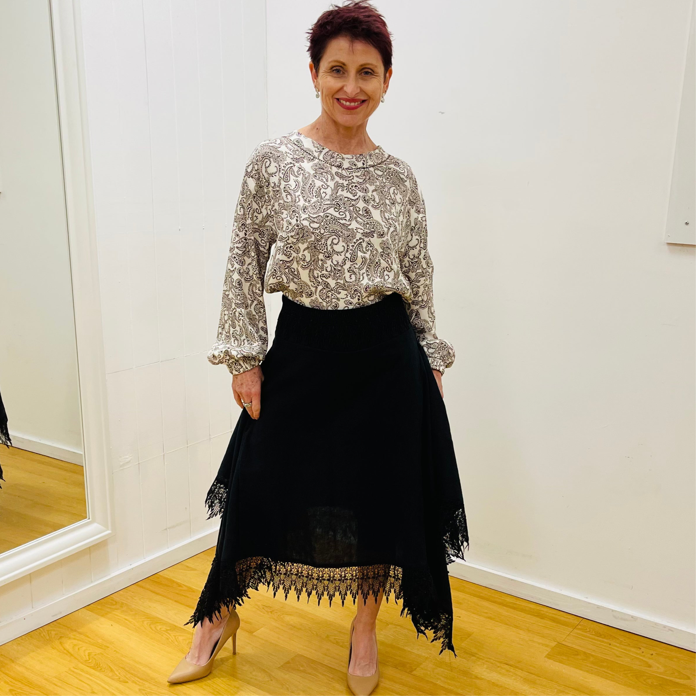 Black linen skirt, with lace detail on waistband and around the handkerchief, uneven, hemline. With paisley pattern printed high round neckline, gathered cuff, long sleeve blouse, top.