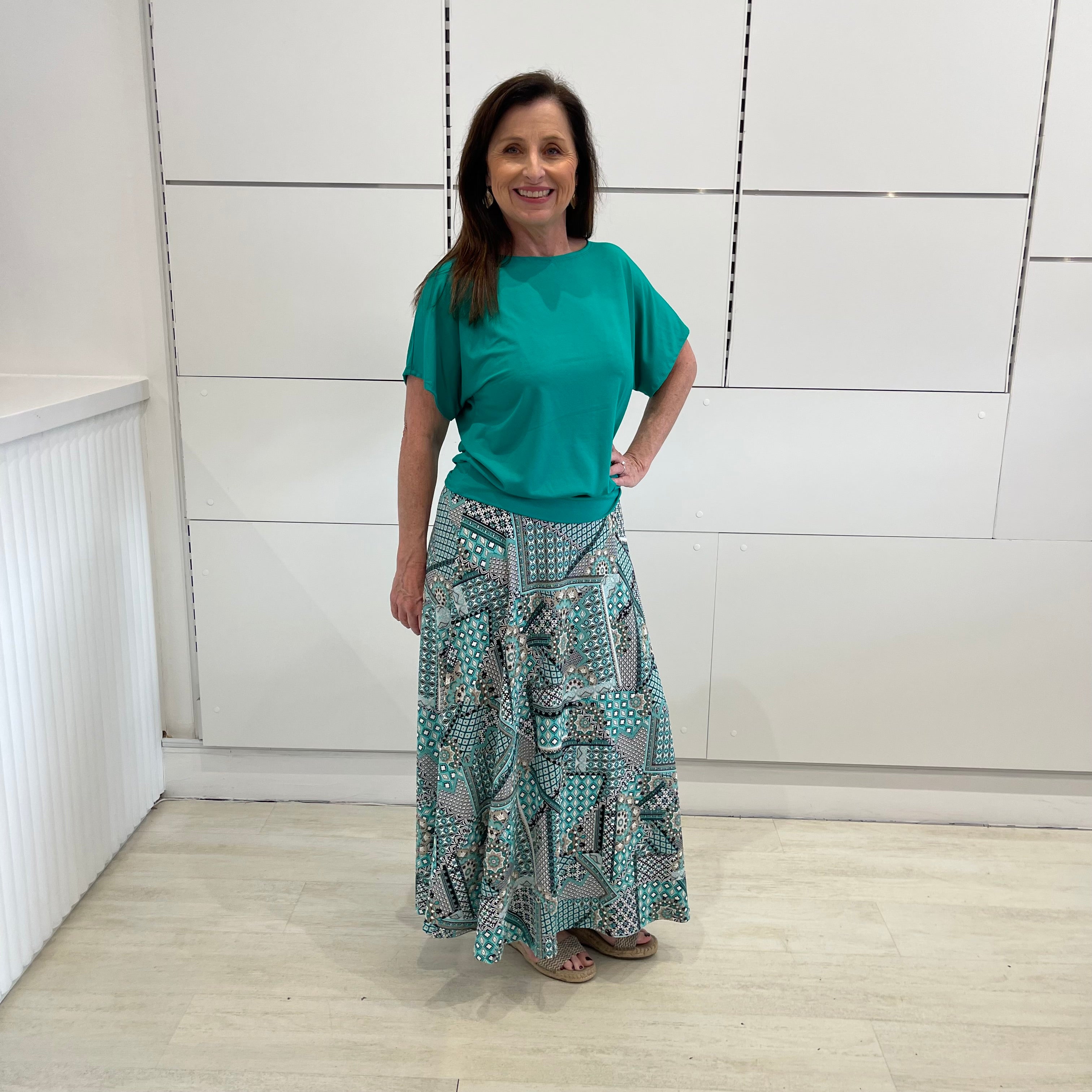 Emerald green bamboo, relaxed fit, scoop neckline , short sleeve, summer top, with band on hem for shape. Worn with long green patterned long, maxi skirt.
