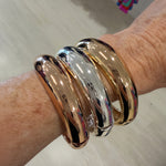 Gold and silver bangles on a wrist with a blurred background