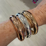 Gold and silver bangles on a wrist with a blurred background