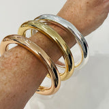 Three gold and silver bracelets on a wrist against a white background