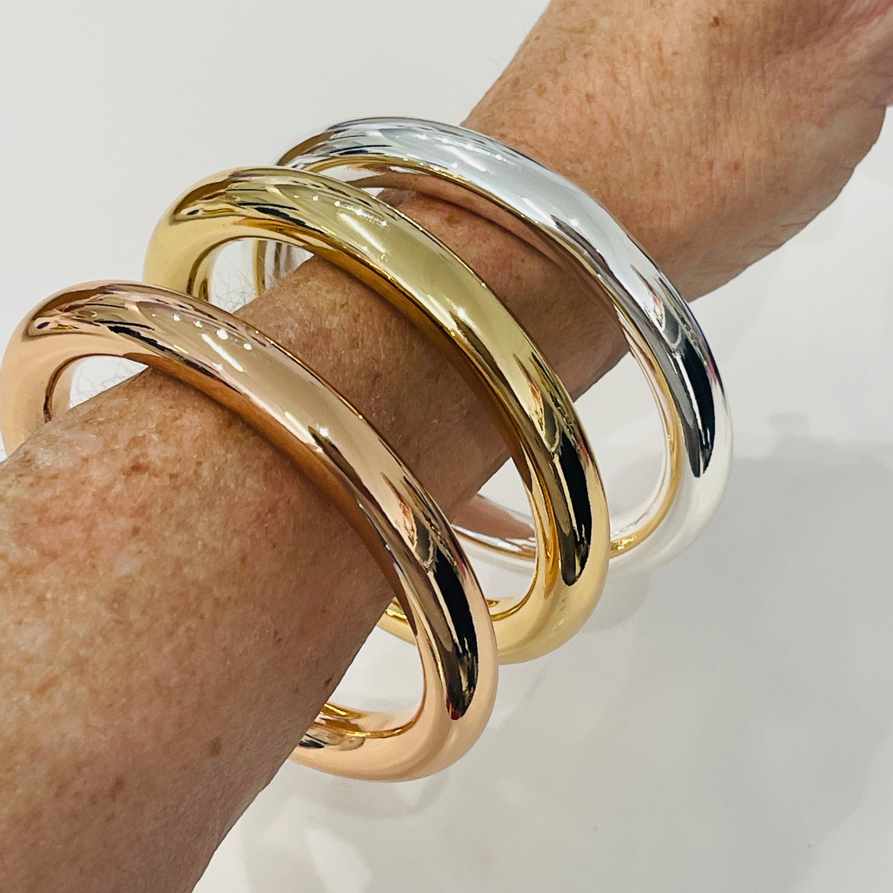 Three gold and silver bracelets on a wrist against a white background
