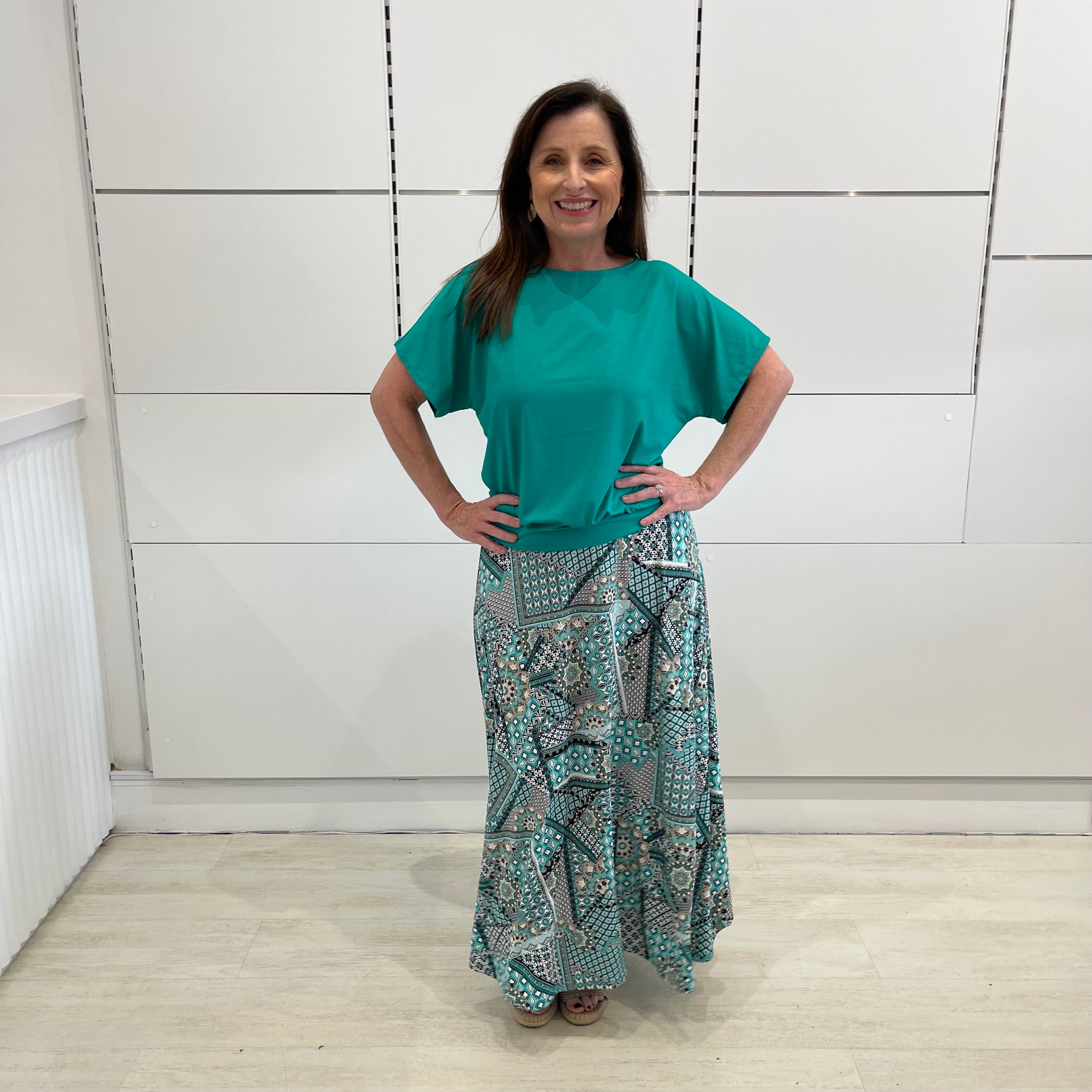 Emerald green bamboo, relaxed fit, scoop neckline , short sleeve, summer top, with band on hem for shape. Worn with long green patterned long, maxi skirt.