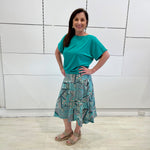 Emerald green bamboo, relaxed fit, scoop neckline , short sleeve, summer top, with band on hem for shape. Worn with long green patterned midi skirt.