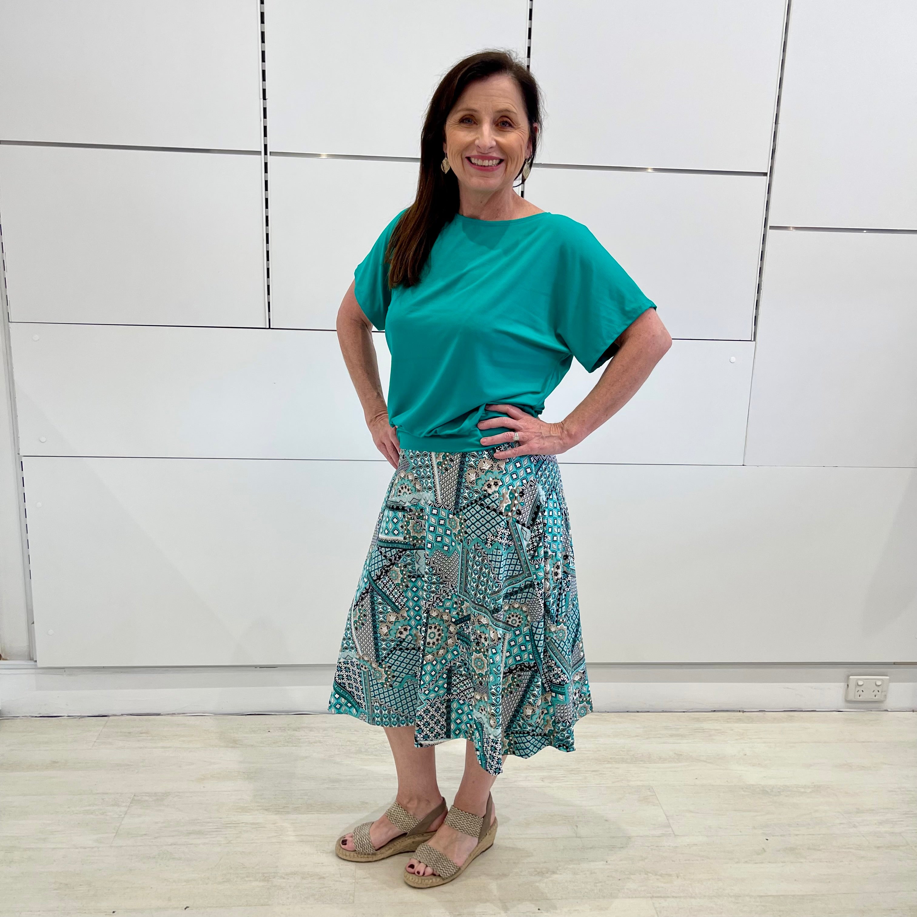 Emerald green bamboo, relaxed fit, scoop neckline , short sleeve, summer top, with band on hem for shape. Worn with long green patterned midi skirt.