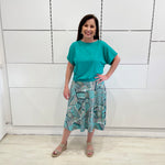 Emerald green bamboo, relaxed fit, scoop neckline , short sleeve, summer top, with band on hem for shape. Worn with long green patterned midi skirt.