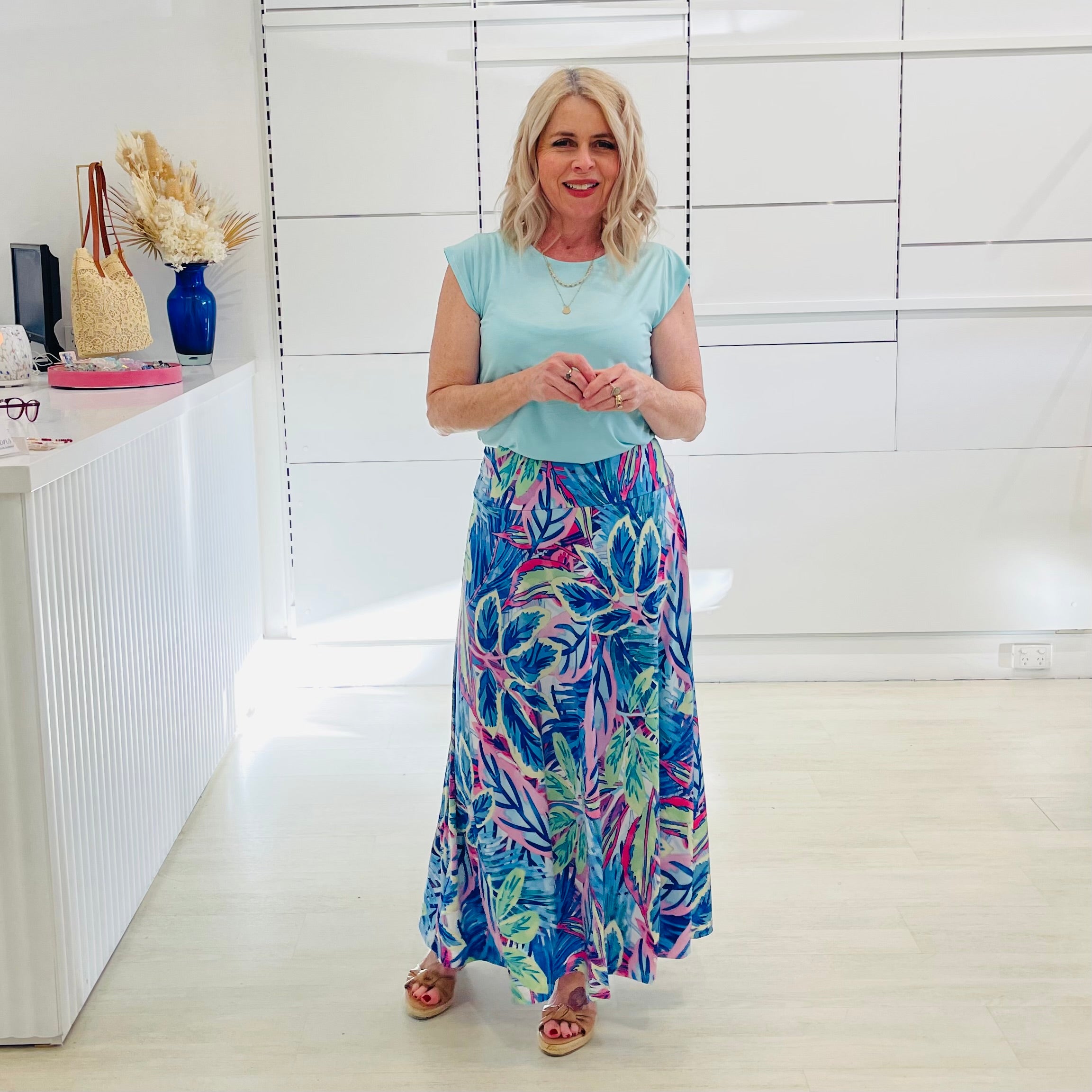 Woman wearing green short sleeve t-shirt with long blue floral skirt. 