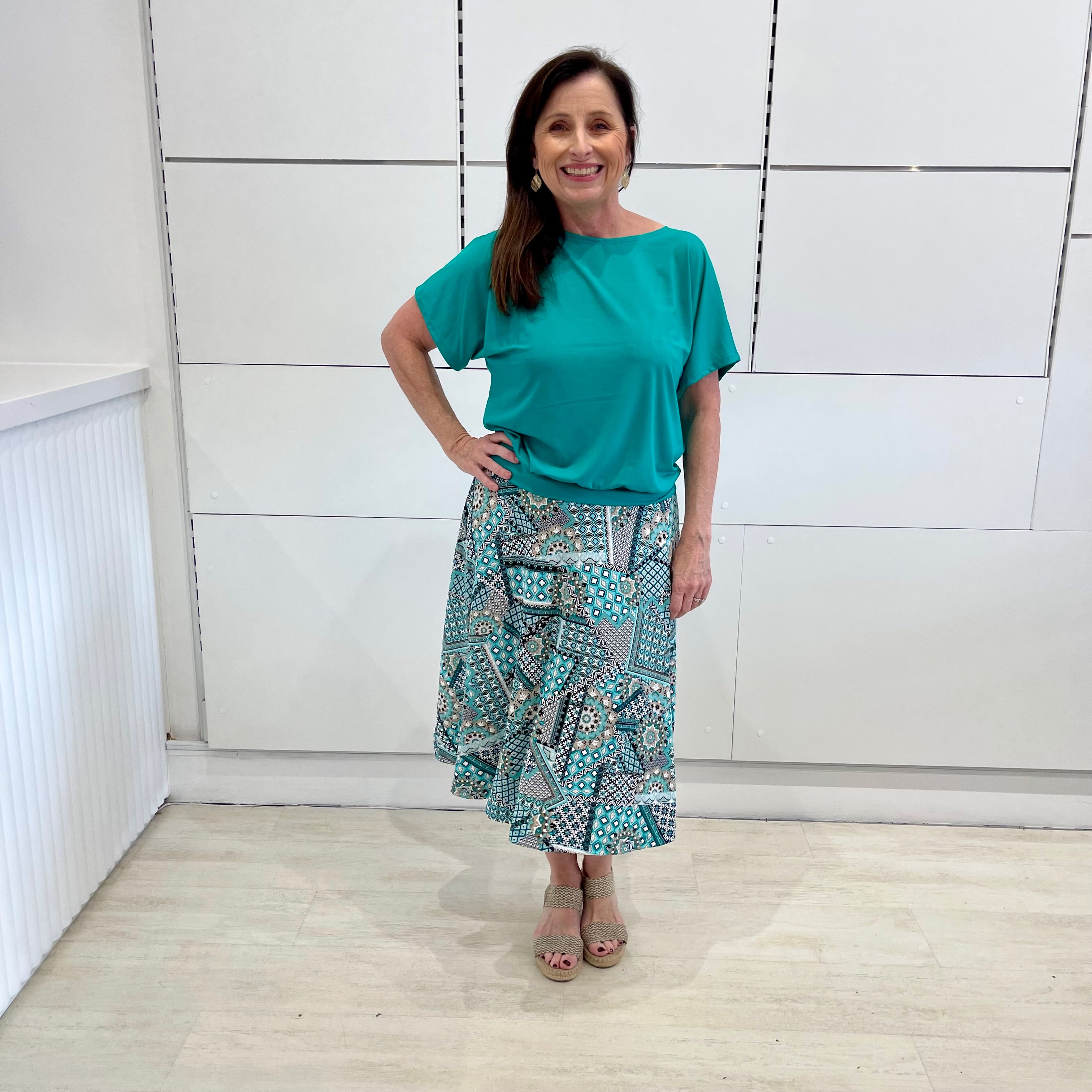 Emerald green bamboo, relaxed fit, scoop neckline , short sleeve, summer top, with band on hem for shape. Worn with long green patterned midi skirt.