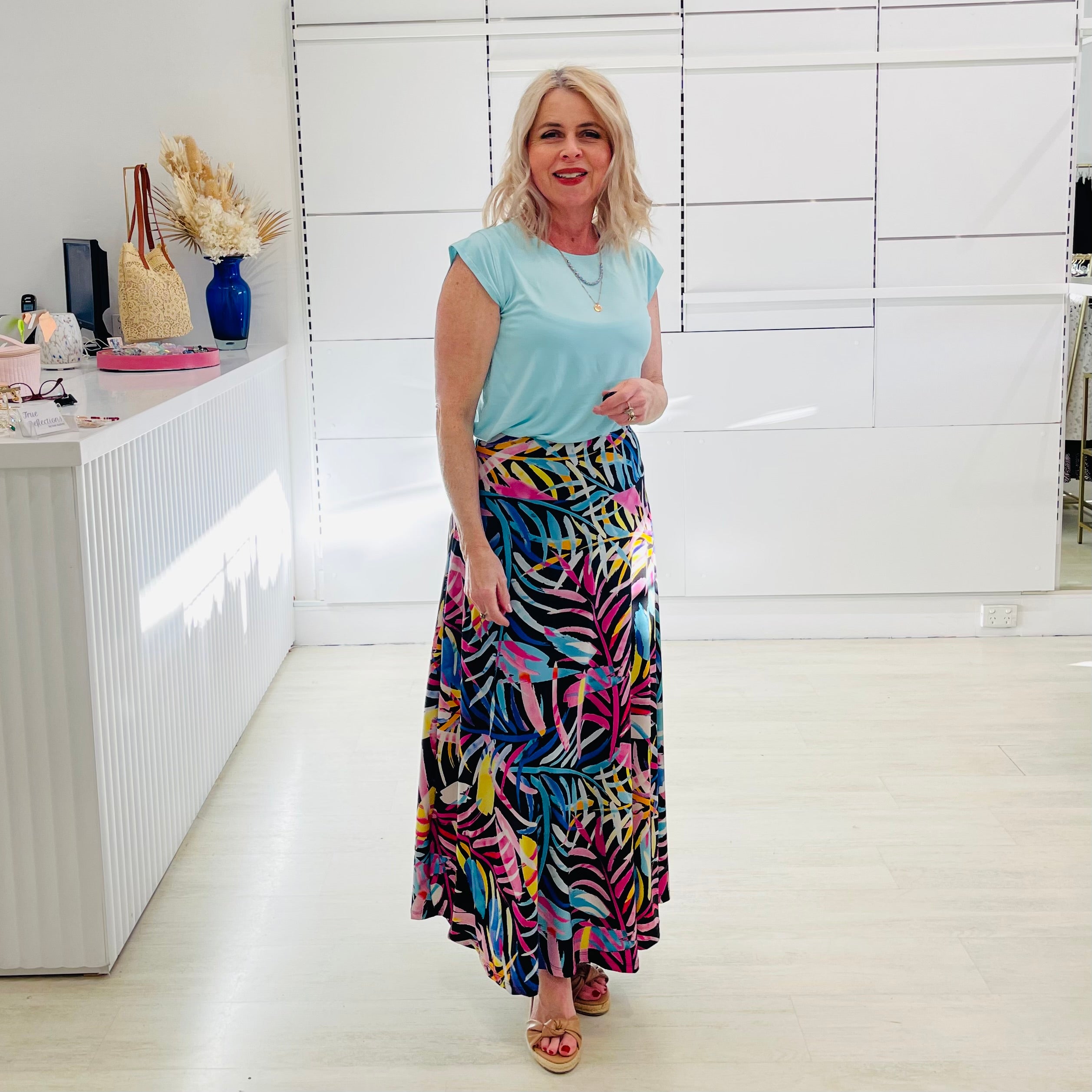 Woman wearing blue t shirt with long floral print skirt. 