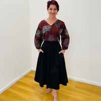 Black, cotton sateen, paneled, midi length, a line skirt, with high waistband and pockets. Worn with deep red color printed pattern floral ,v neckline, 3/4 length sleeve blouse.