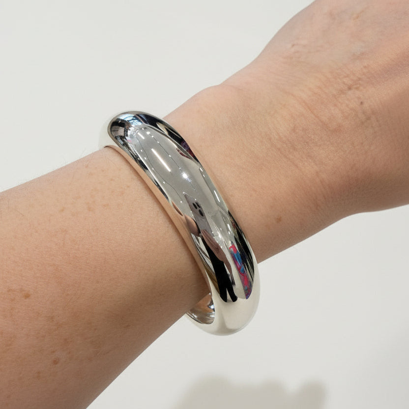 Silver bangle on an elderly person's wrist with a blurred background