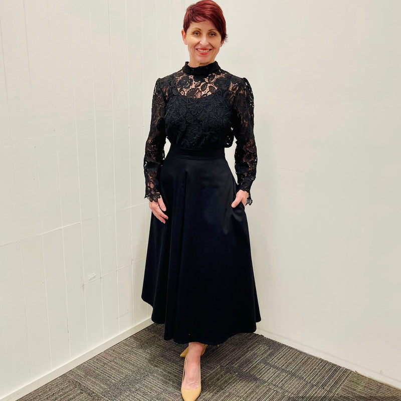 Black, cotton sateen, paneled, midi length, a line skirt, with high waistband and pockets. Worn with black sheer lace, high neckline , long sleeve blouse