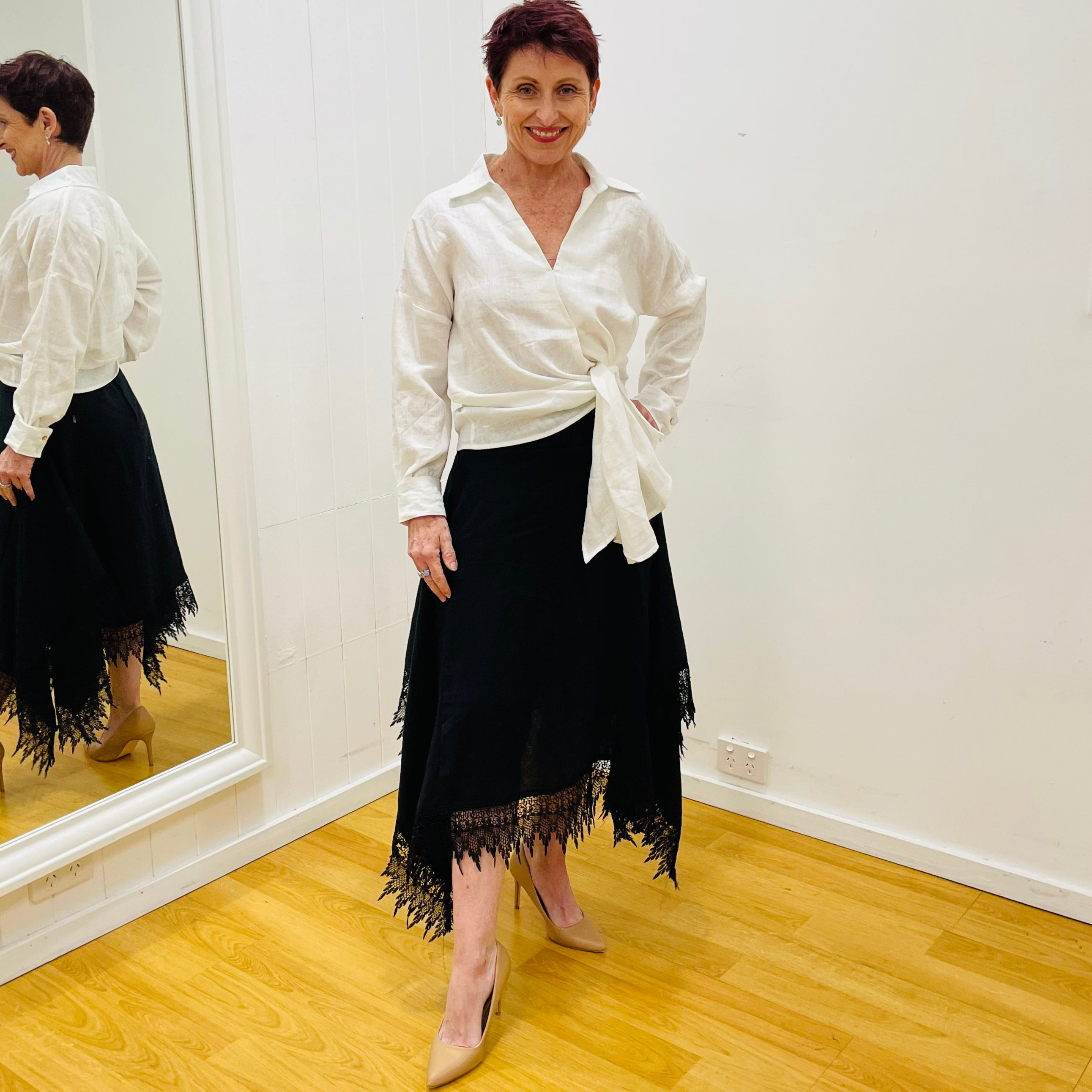 Black linen skirt, with lace detail on waistband and around the handkerchief, uneven, hemline. With white, long sleeve, side tie, women's  linen shirt.